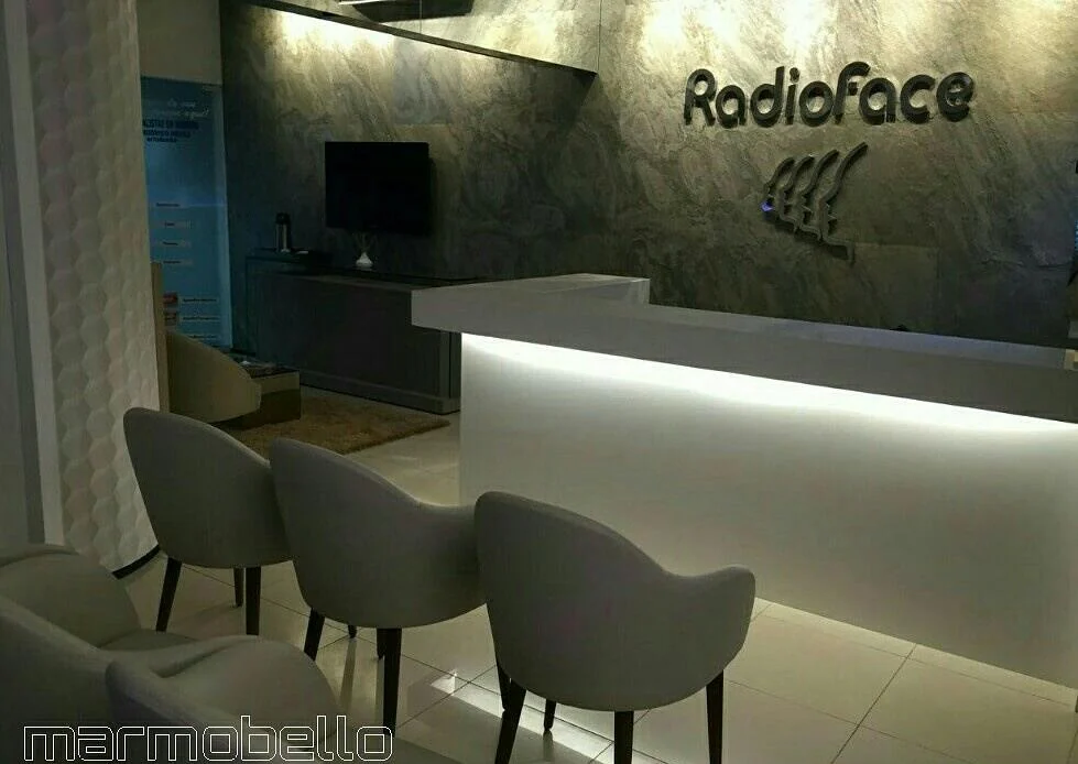 Recepção corporativa com balcão iluminado e superfície em pedra